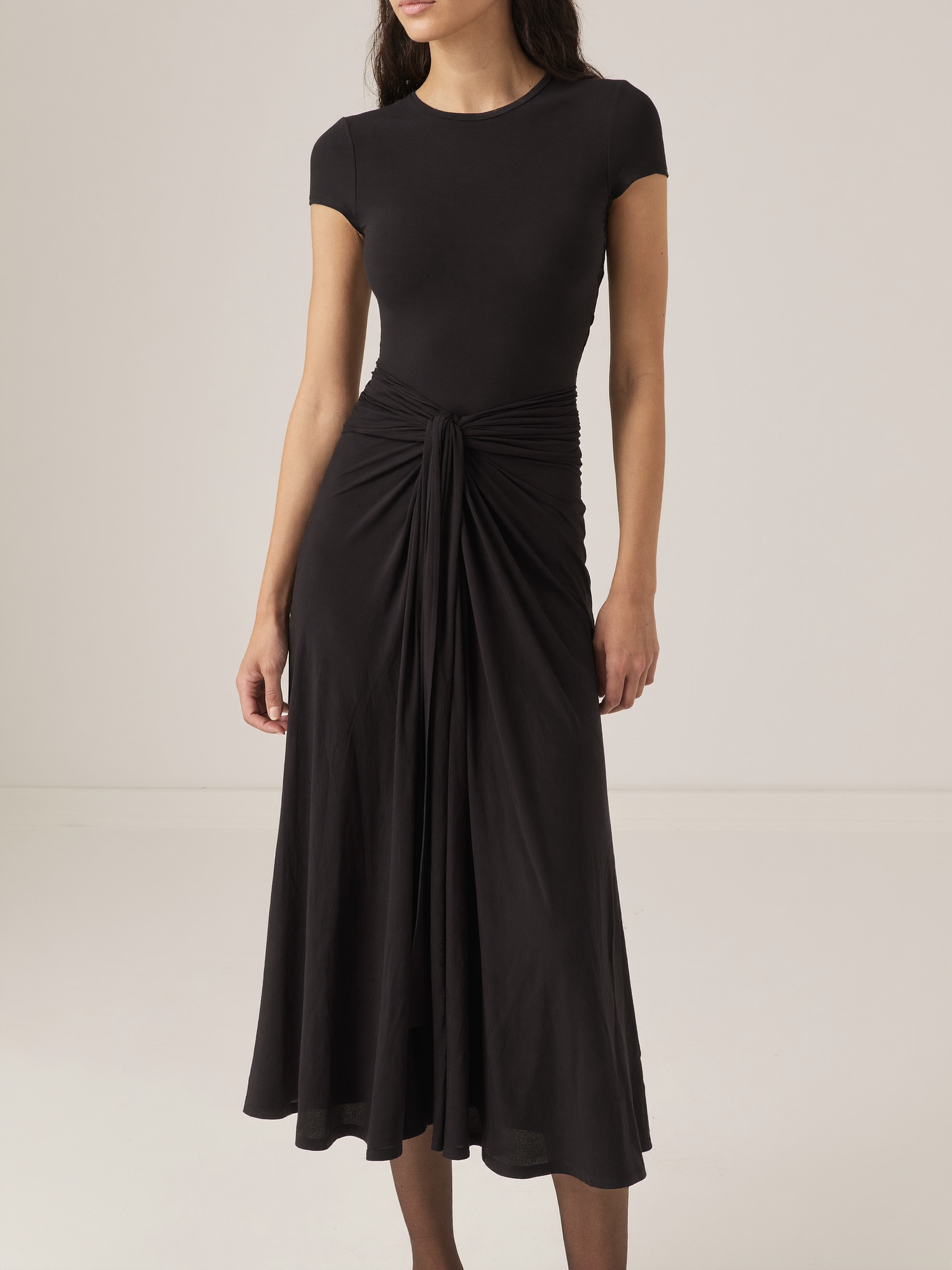 Model wearing black bodycon twist-waist cocktail dress