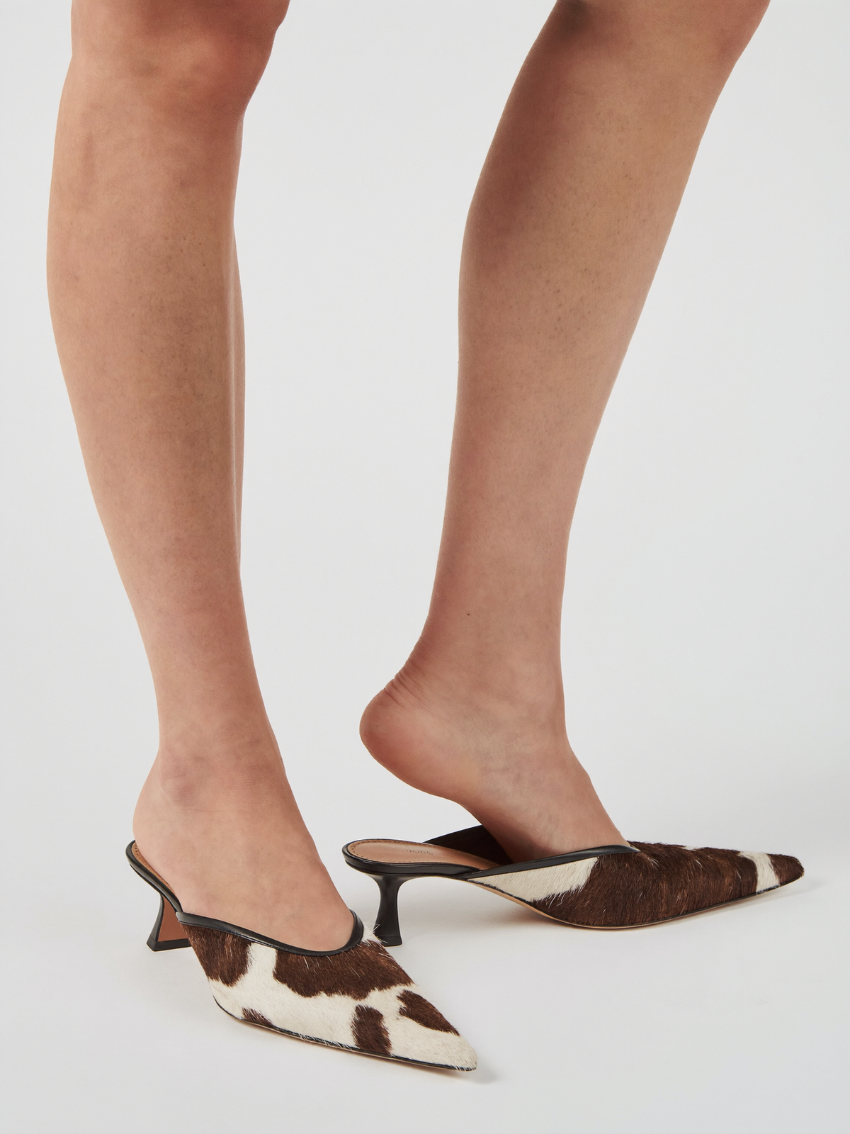 Model wearing cow print calf hair loafer mules